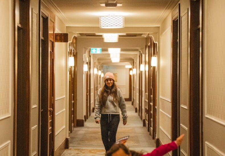 Two children having fun running down a well-lit hotel corridor.